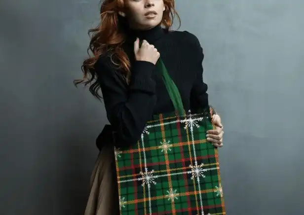Woman holding the Winter Whispers Plaid Tote Bag - Embracing cozy glamour with classic green plaid and snowflakes.